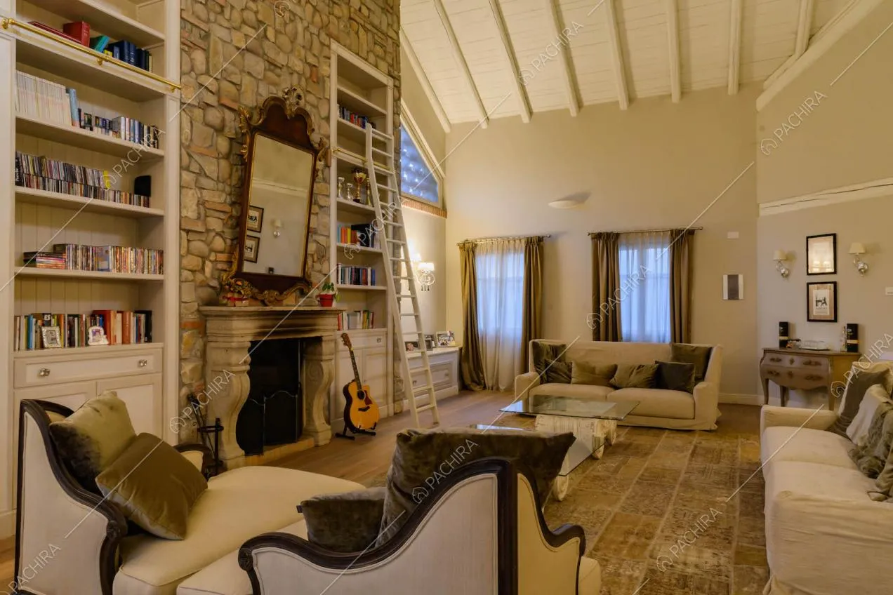 Divani di design nel salotto con soffitto in travi in legno a vista, camino e pavimento in parquet