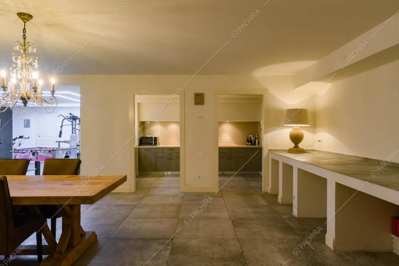 Grande sala con vista sulla cucina a parete, tavolo da pranzo in legno e palestra
