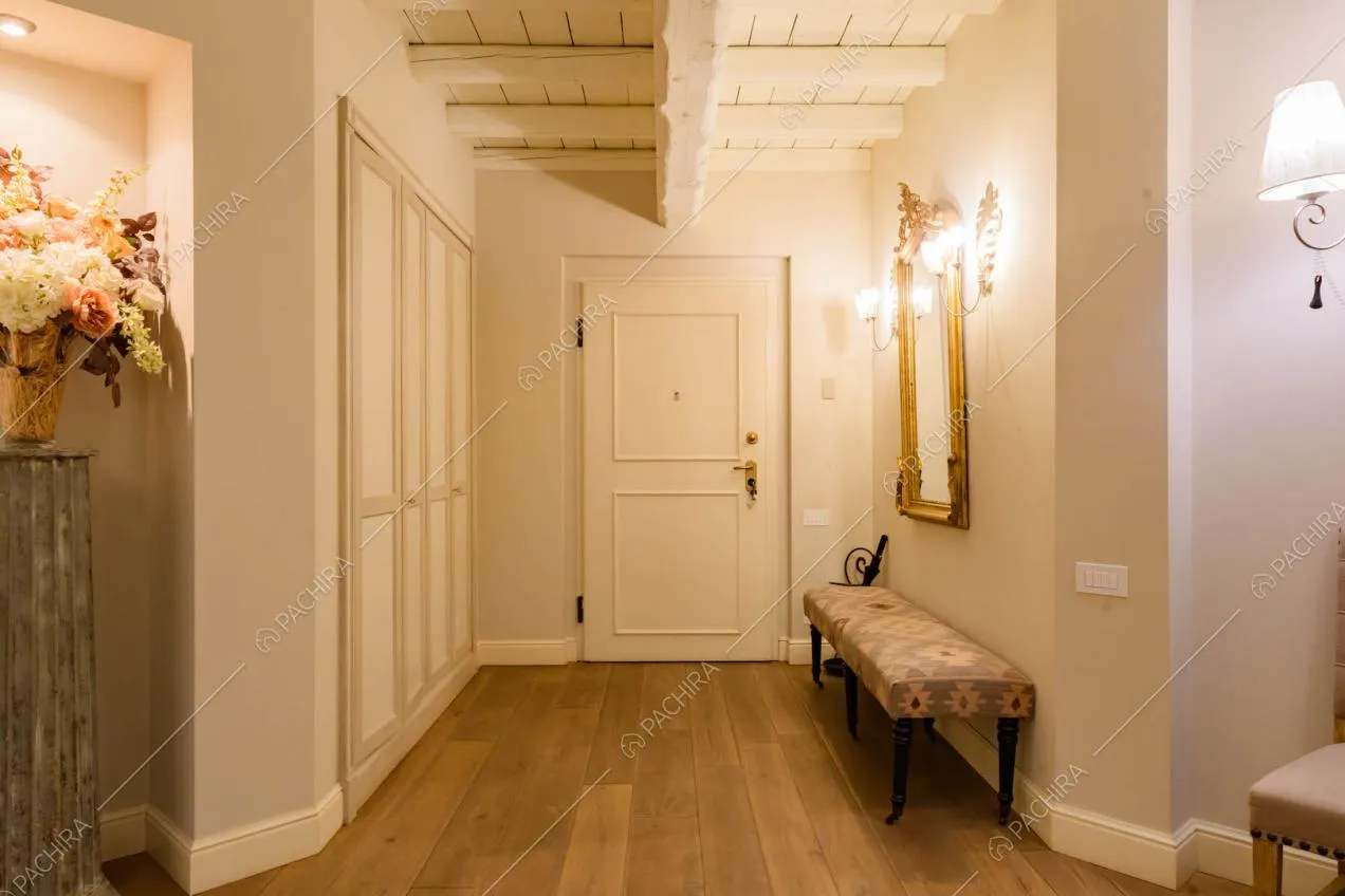 Ingresso della location con porta bianca con boiserie, pavimento in parquet e pareti grigie