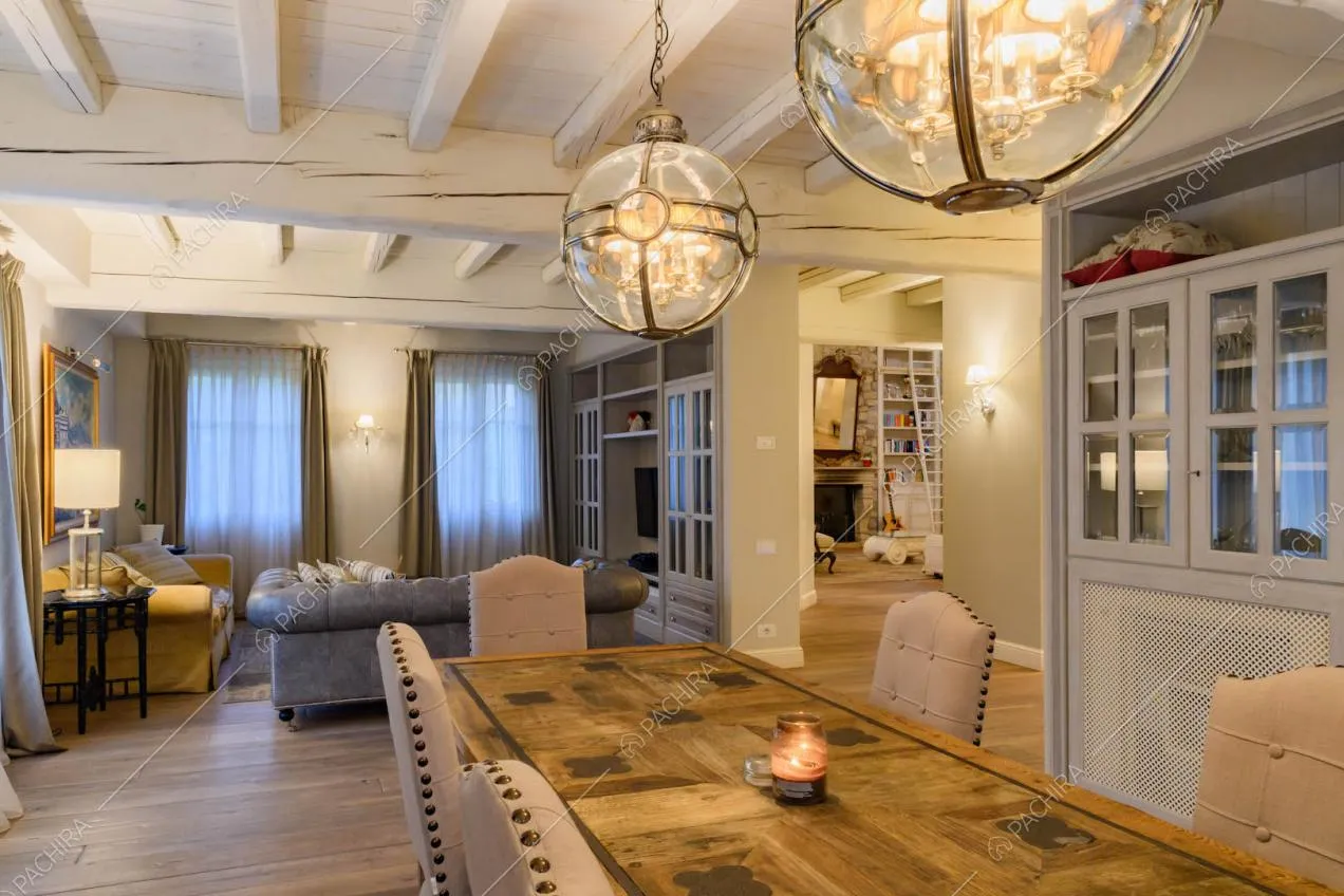 Tavolo da pranzo di legno, vista sul divano grigio in pelle, credenza e pavimento in parquet