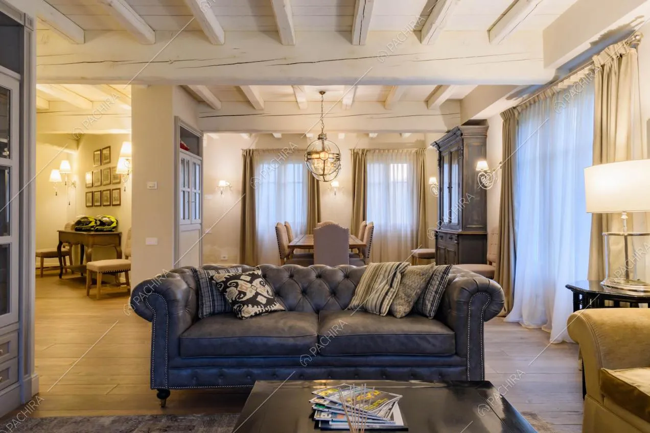 Divano in pelle nella sala con tavolo da pranzo, pavimento in parquet e vetrate