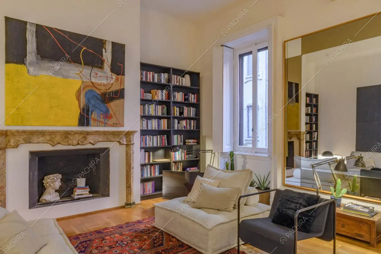 Camino con cornice decorativa nella sala con pavimento in parquet e pareti bianche