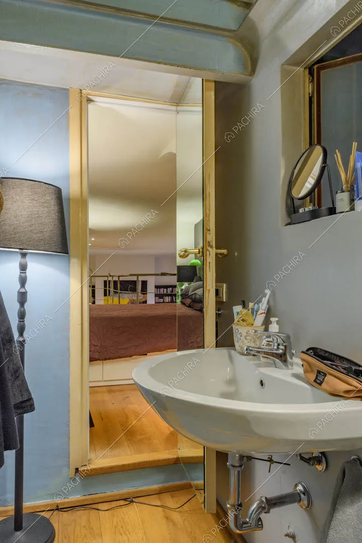 Dal lavandino del bagno con parete azzurra vista sul letto matrimoniale