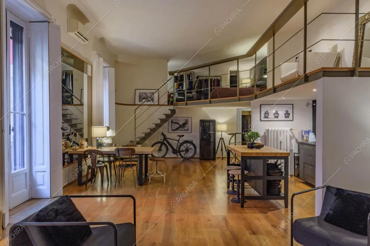 Poltrone nere di design nella luminosa sala con porte-finestre e soppalco
