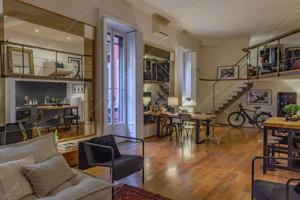 Sala con pavimento in parquet, grande specchio e soppalco