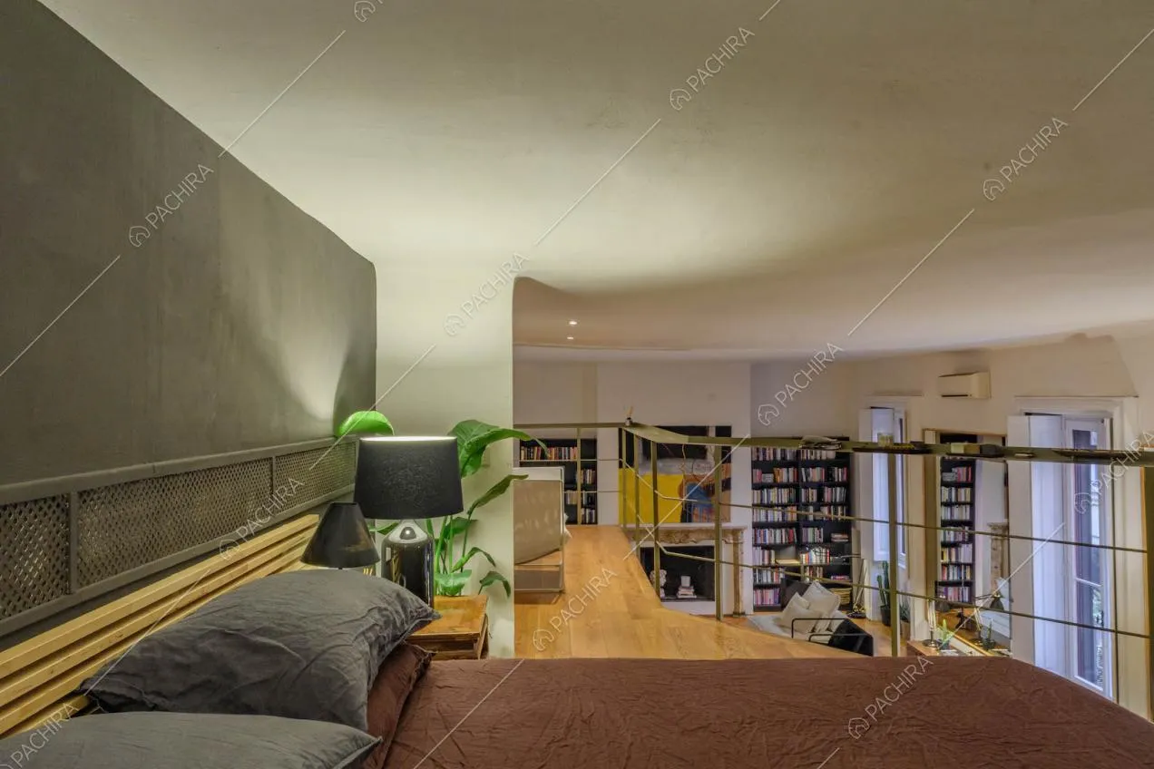 Letto matrimoniale sul soppalco con pavimento in parquet e vista sulla sala