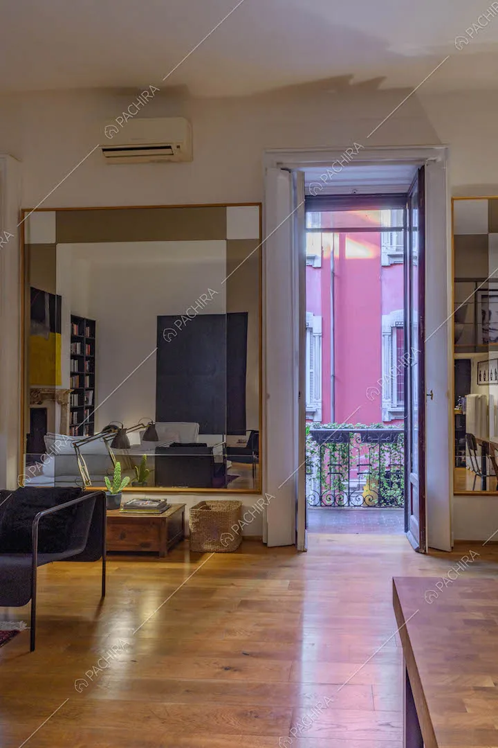 Tavolo da pranzo nell'open space con divano, porta-finestra e pavimento in parquet