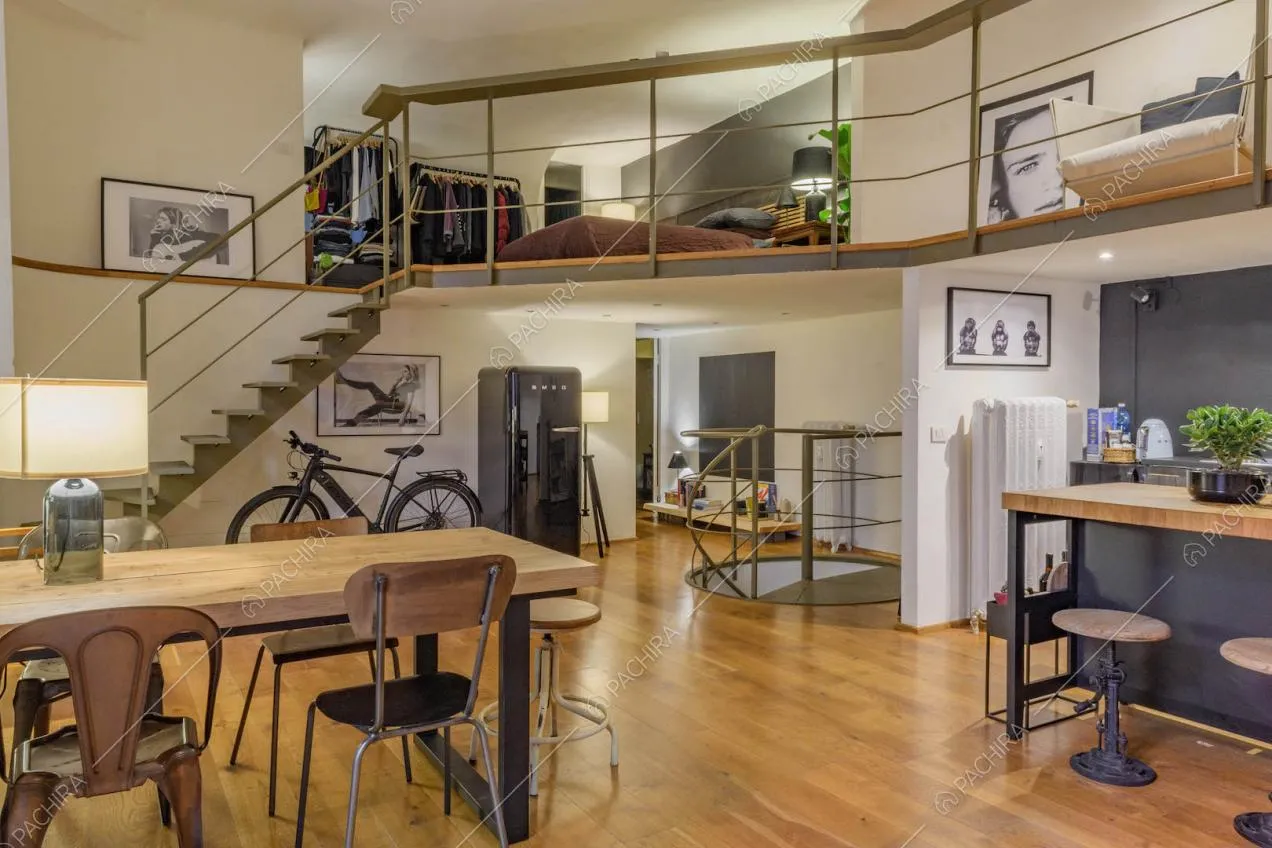 Tavolo da pranzo in legno nell'open space con cucina a vista, soppalco e scala a chiocciola