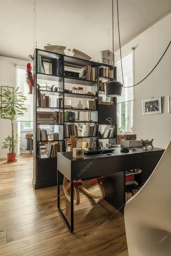 Scrivania nera nell'ingresso con pavimento in parquet e poltrona bianca di design a forma di visto