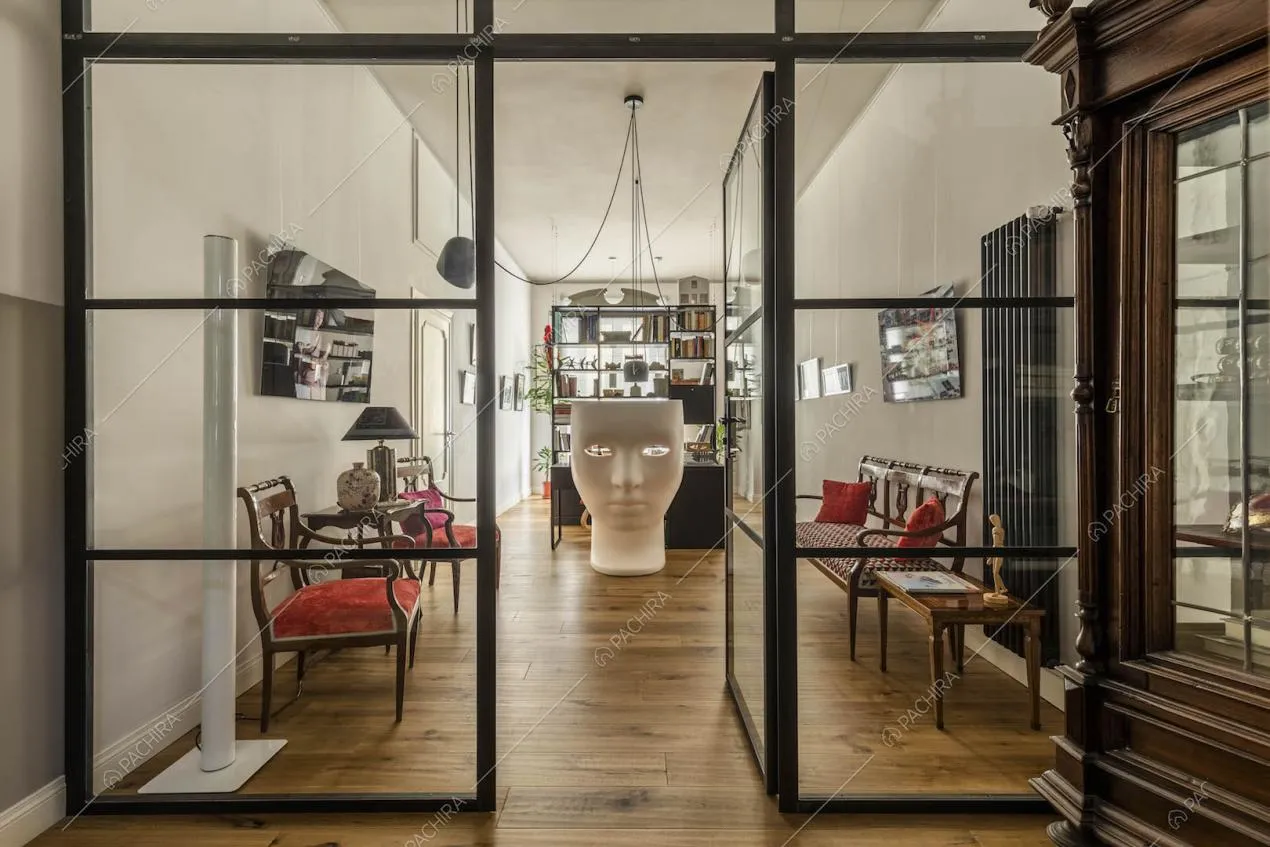 Ingresso della location con pavimento in parquet e parete in vetro e metallo nero
