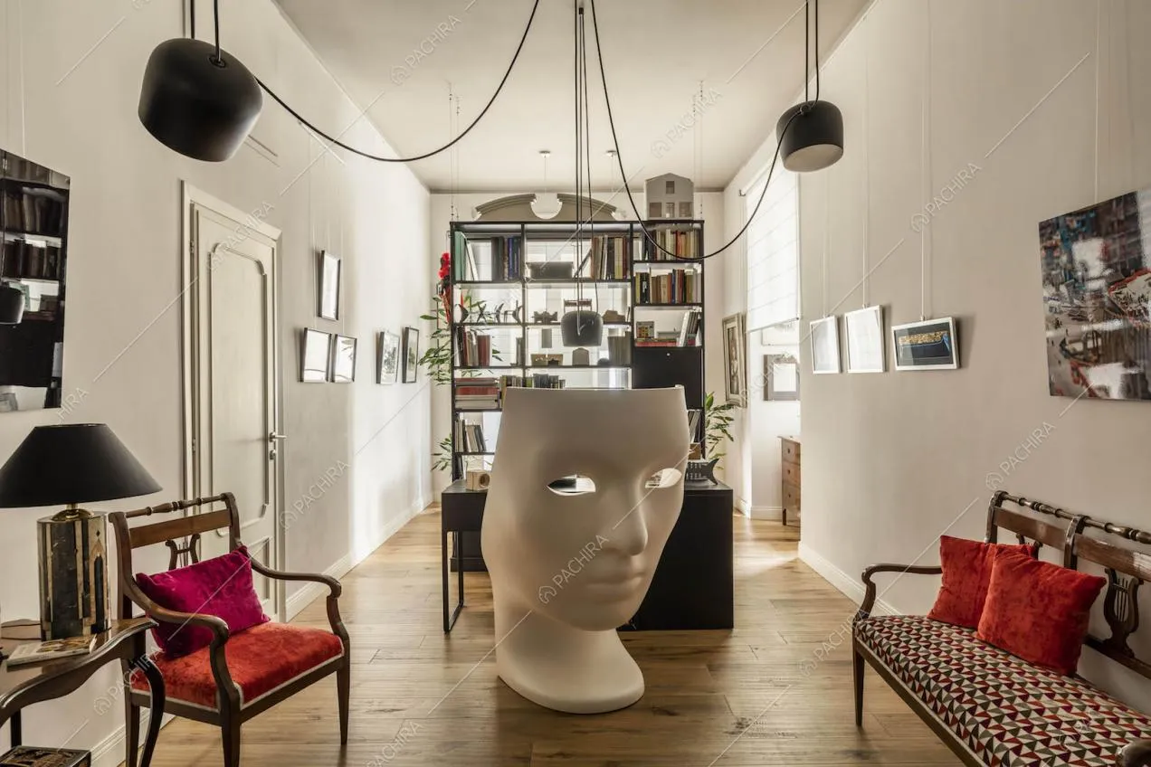 Ingresso con lampade e poltrona di design, pavimento in parquet e pareti bianche