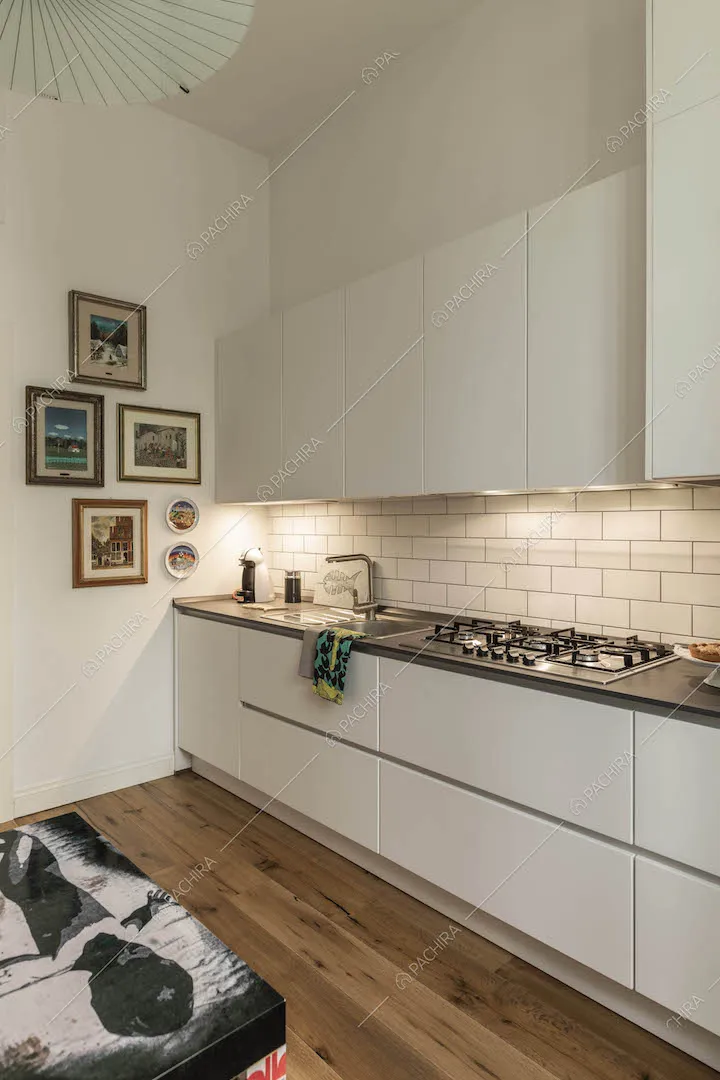 Cucina a parete con fornelli a gas, pareti bianche e pavimento in parquet