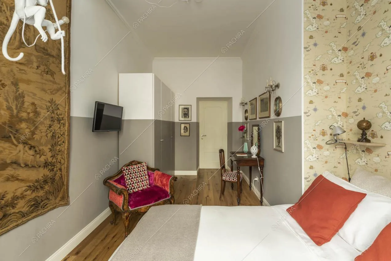 Letto matrimoniale nella camera con pavimento in parquet, pareti bianche e grigie e carta da parati
