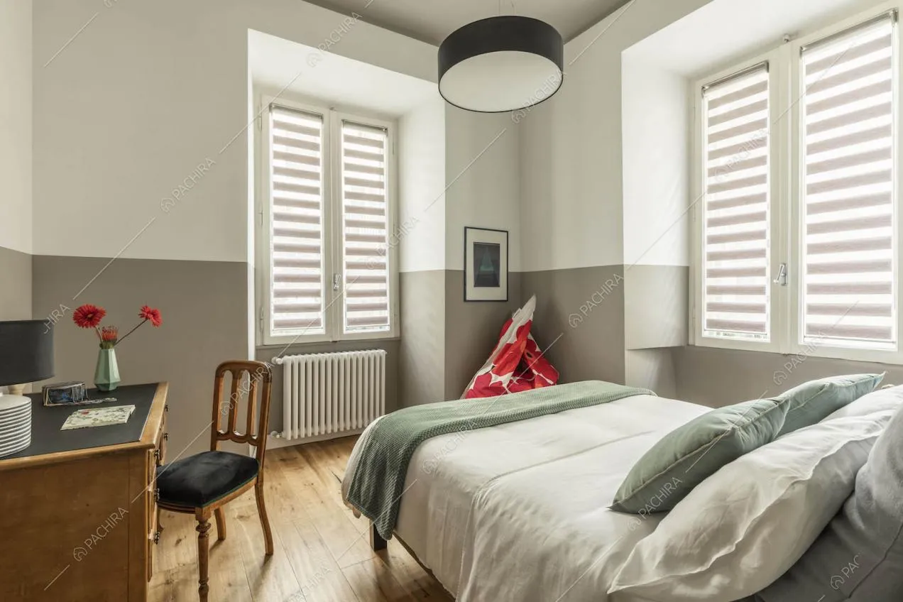Luminosa camera da letto matrimoniale con pavimento in parquet e pareti bianche e grigie