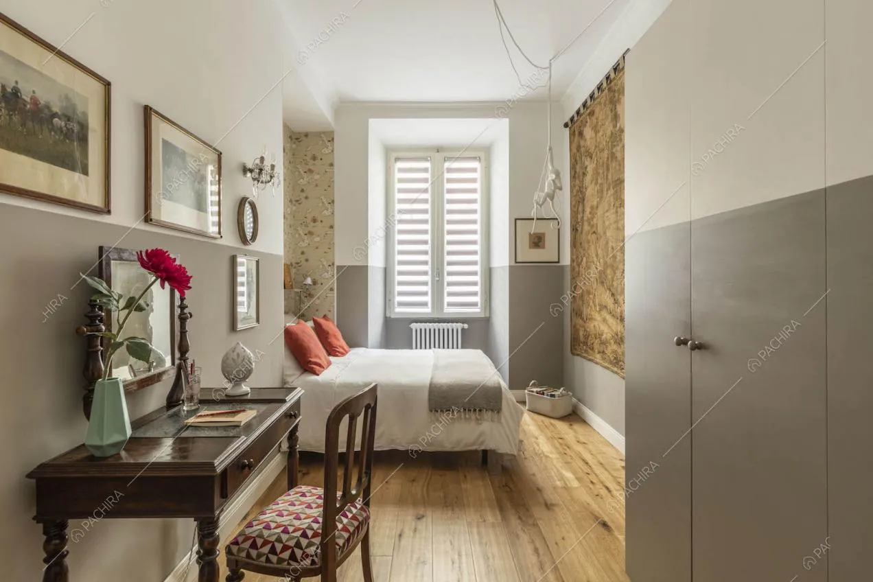 Camera da letto matrimoniale con pavimento in parquet, scrivania e carta da parati