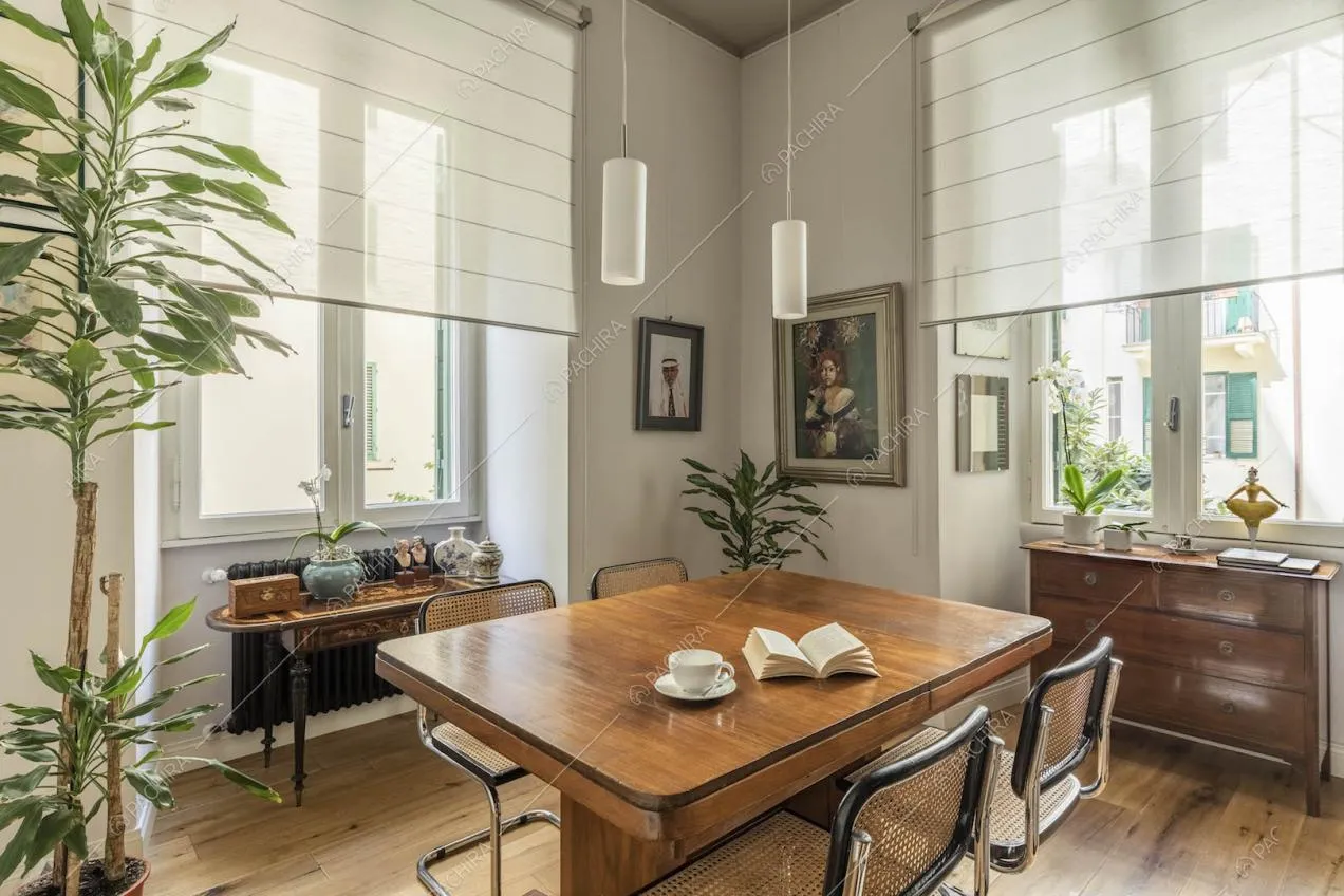 Tavolo da pranzo e sedie vintage nella sala con ampie finestre e pavimento in parquet
