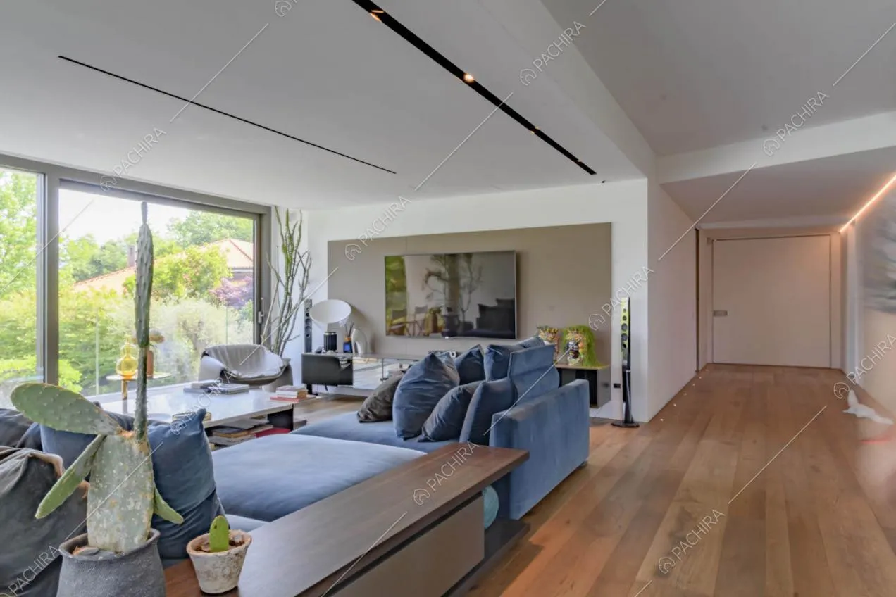 Divani blu nella sala con pavimento in parquet, pareti bianche e grandi vetrate