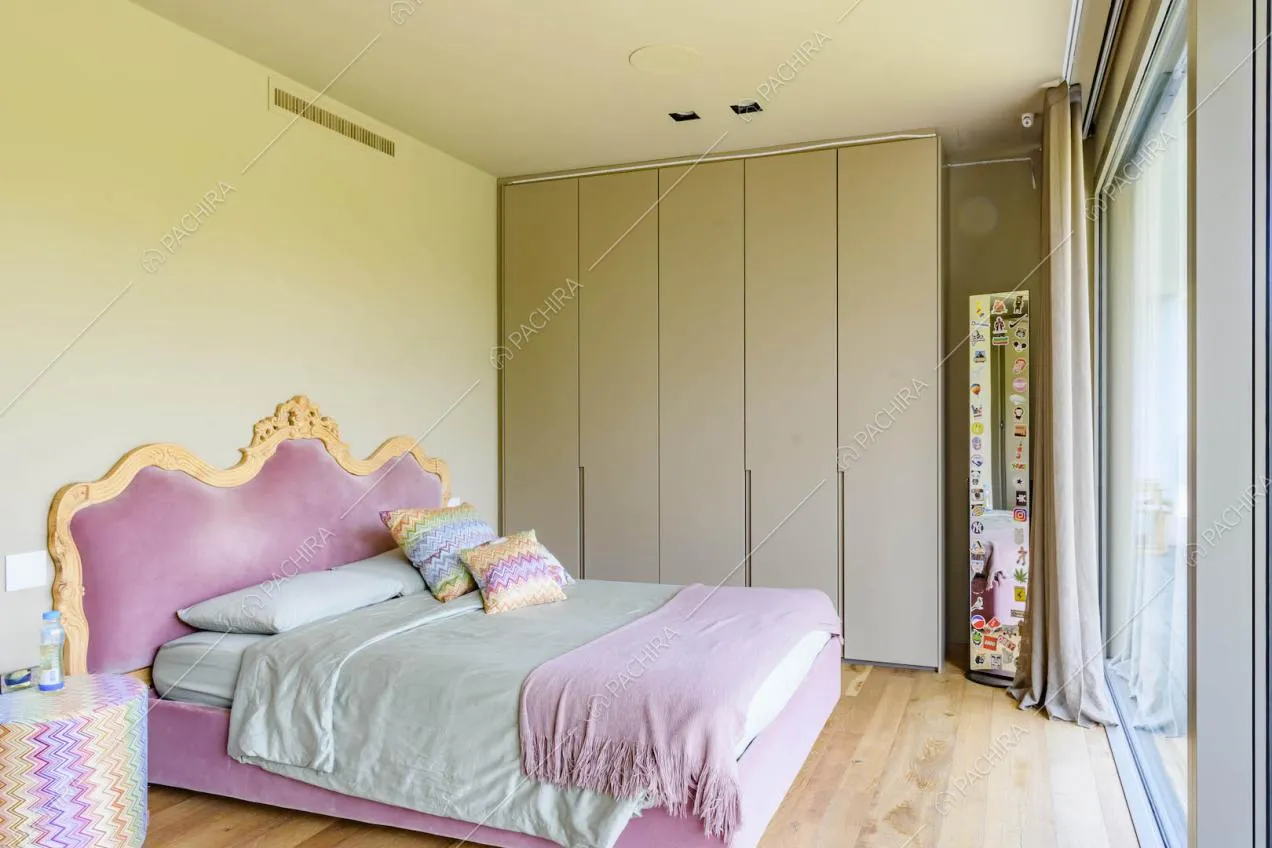 Luminosa camera da letto matrimoniale con struttura in velluto rosa e pavimento in parquet