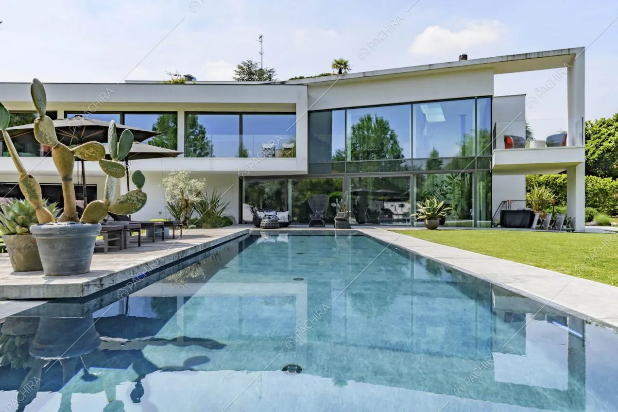 Dalla grande piscina nel giardino vista sulla location con grandi vetrate e veranda