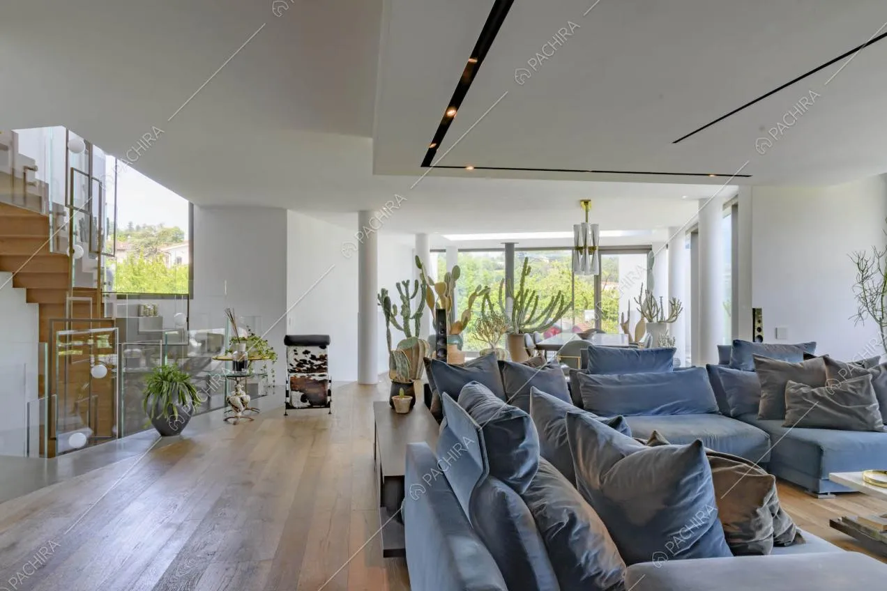 Sala con pavimento in parquet, divani blu, pareti bianche e scale