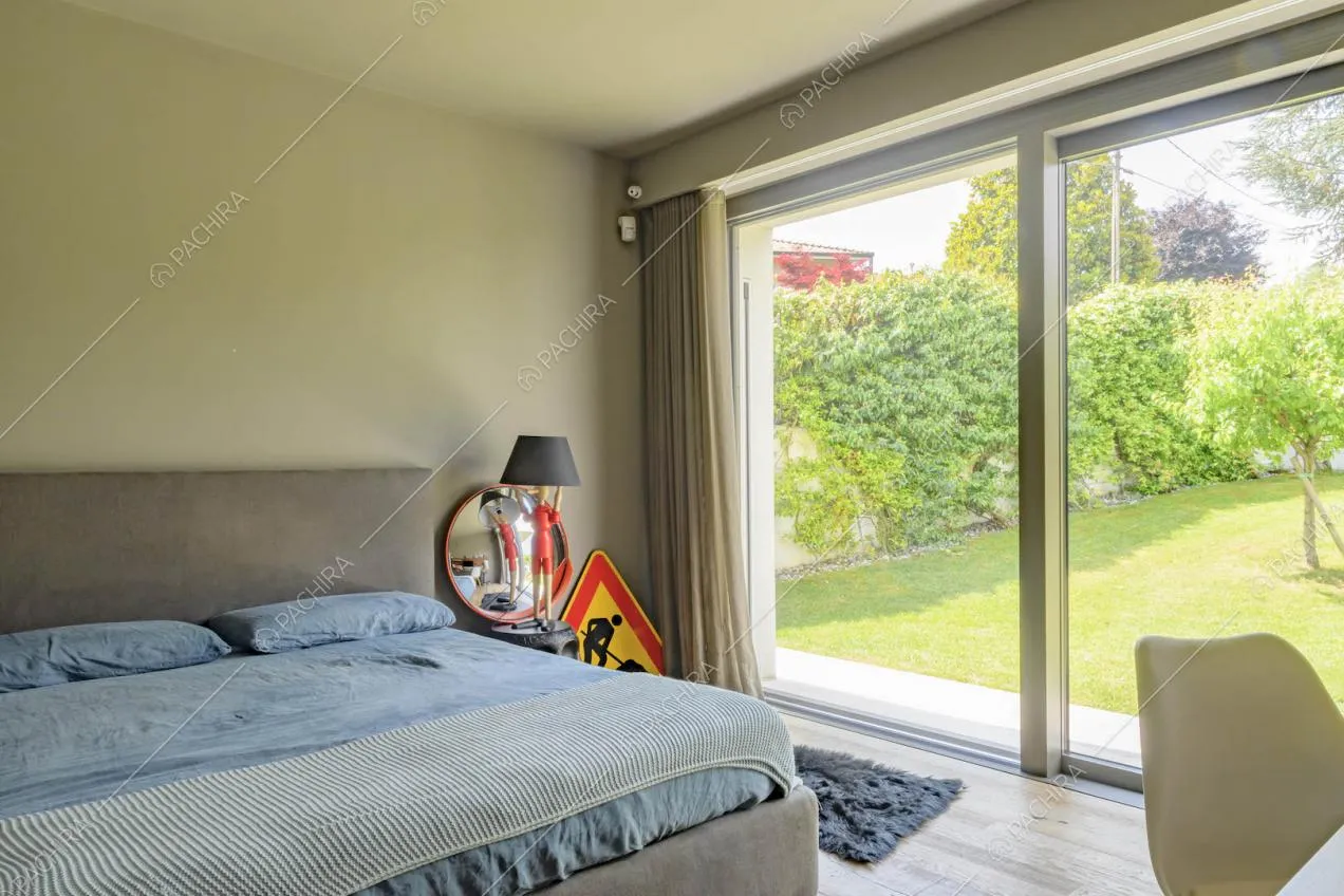 Letto matrimoniale nella camera con pavimento in parquet e porta-finestra con vista sul giardino
