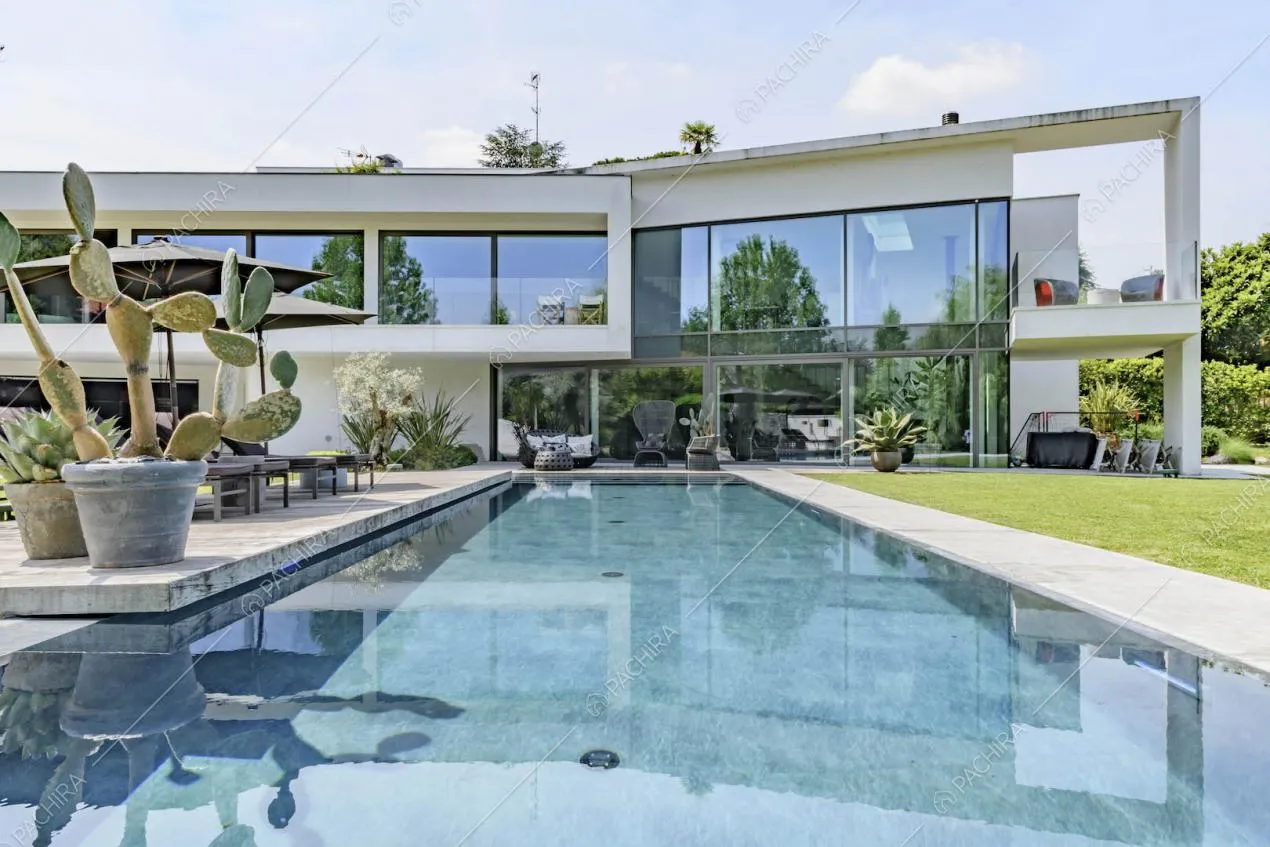 Dalla grande piscina nel giardino vista sulla location con grandi vetrate e veranda