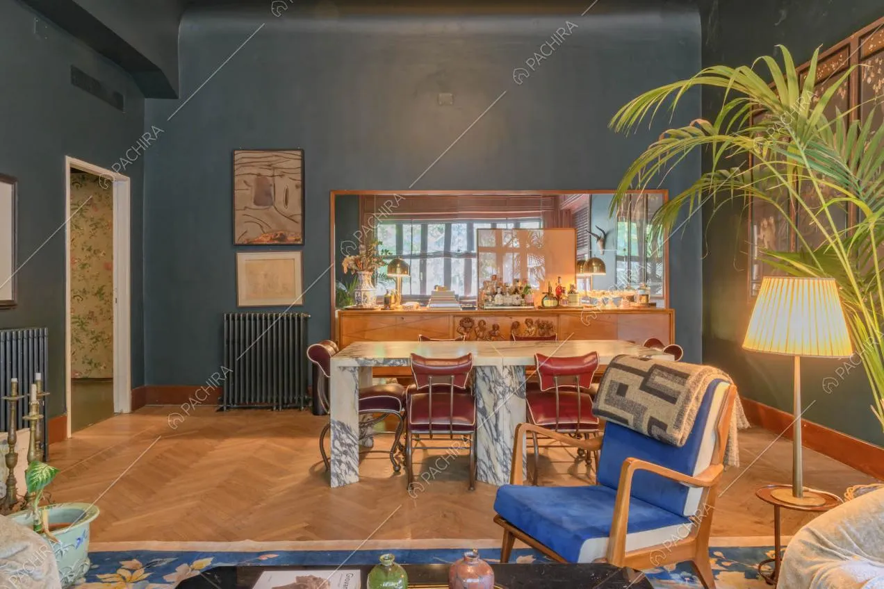 Salotto con pavimento in parquet a spina di pesce, tavolo da pranzo e pareti blu