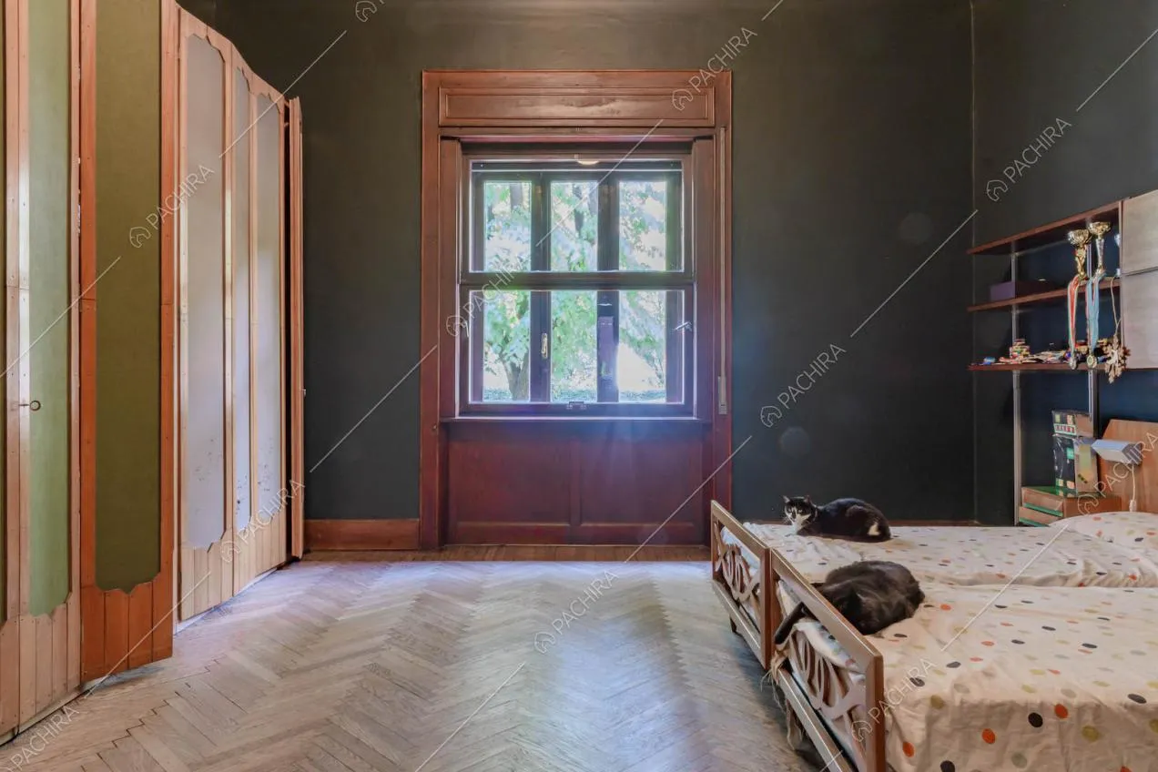 Camera da letto matrimoniale con pavimento in parquet a spina di pesce e finestra con boiserie