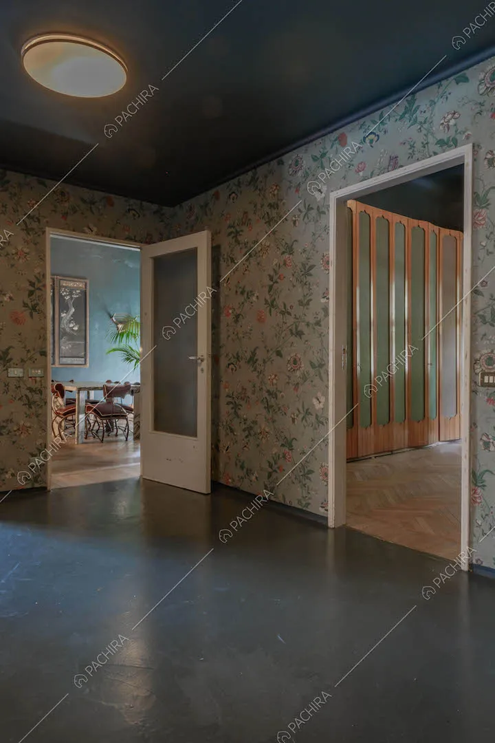 Dall'atrio con carta da parati, pavimento e soffitto blu, vista su salotto e camera da letto