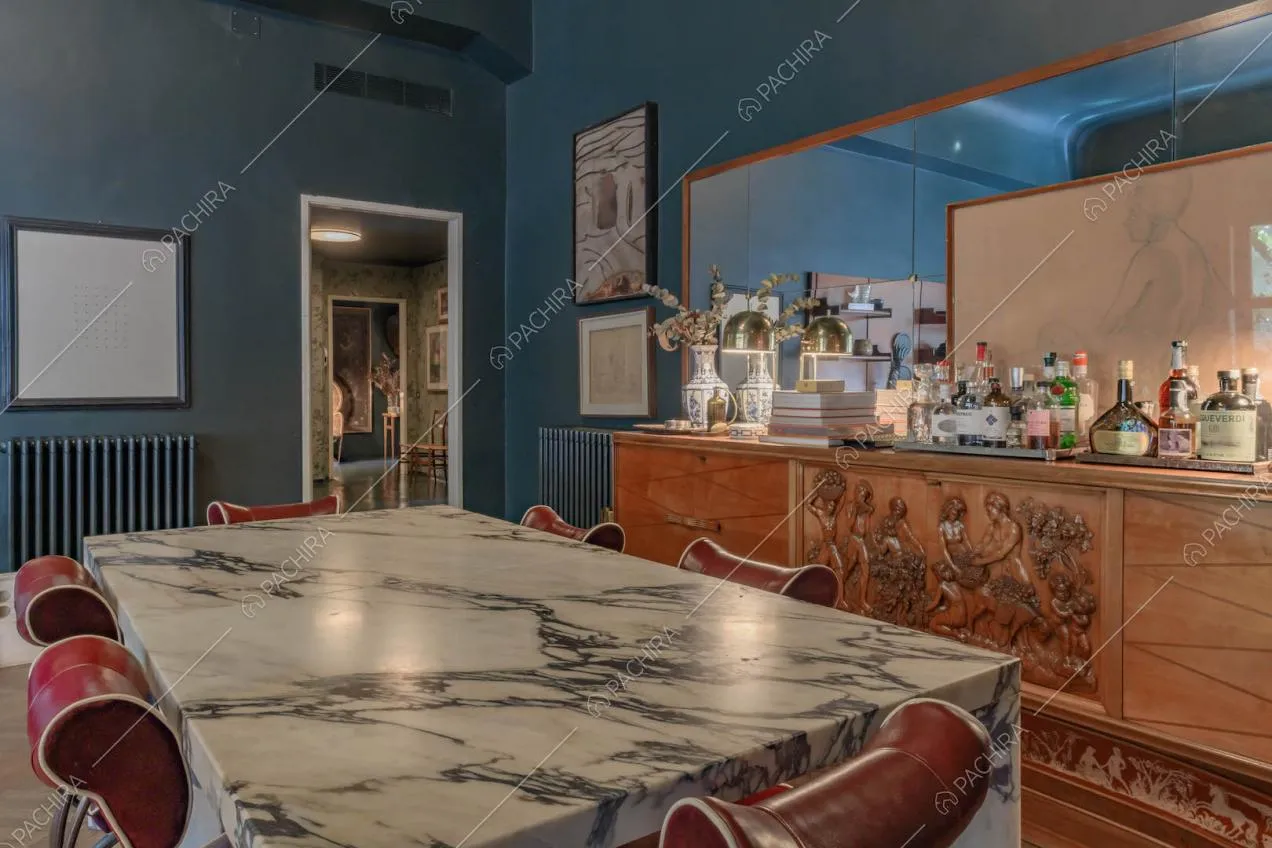 Tavolo in marmo e sedie rosse di design nel salotto con pareti blu e vista sul corridoio