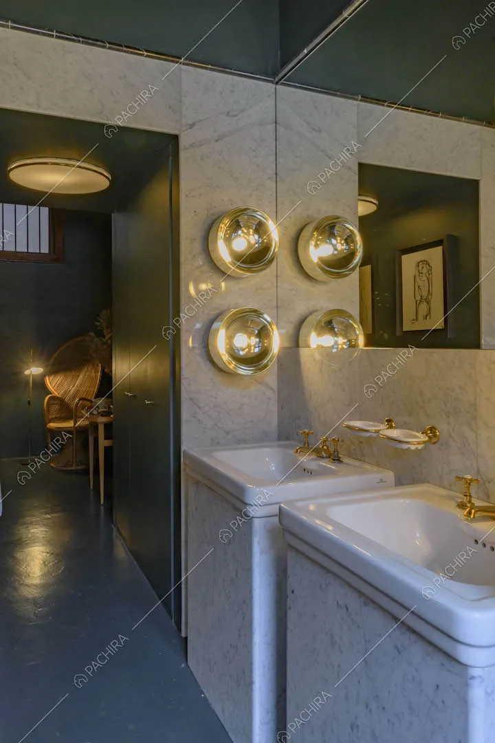 Lavandini nel bagno con grande specchio, parete in marmo e pavimento blu