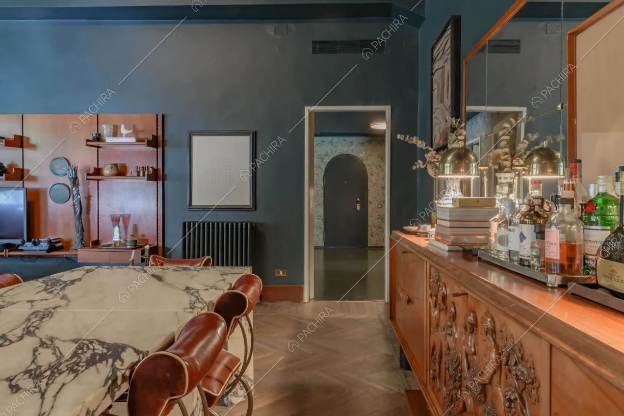 Dal tavolo da pranzo in marmo con sedie rosse di design vista sul corridoio con carta da parati