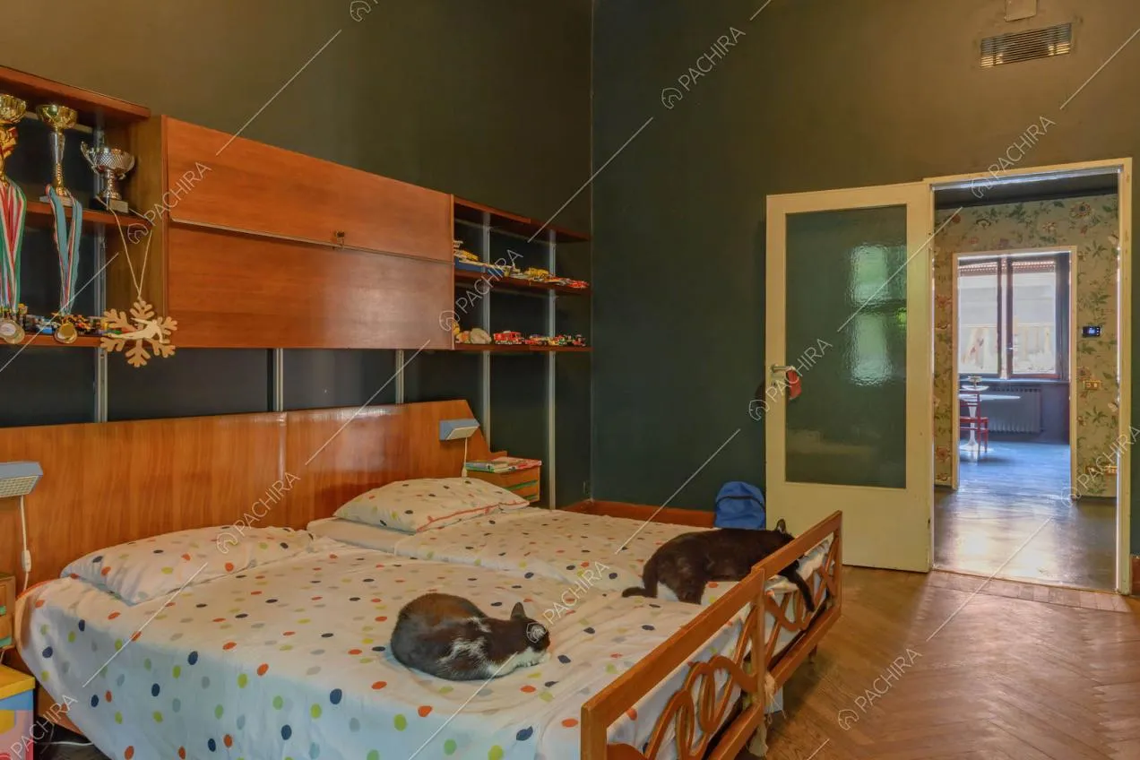 Letto matrimoniale nella camera con pavimento in parquet e vista sulla cucina