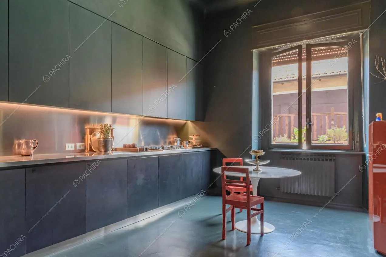 Cucina total blue a parete con fornelli a gas e tavolo da pranzo in marmo con sedie rosse