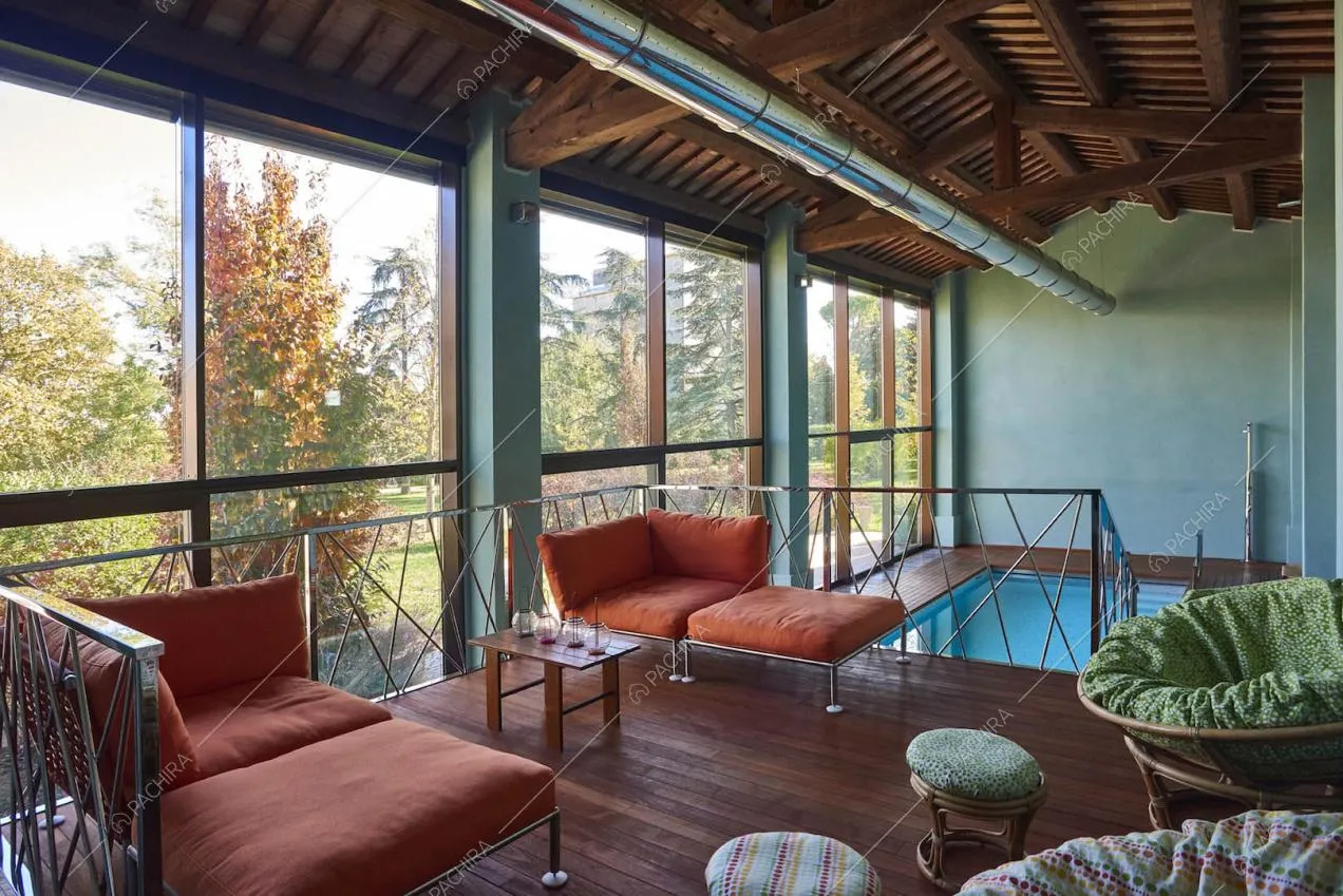 Dal soppalco con poltrone arancioni e pouf vista sulla piscina
