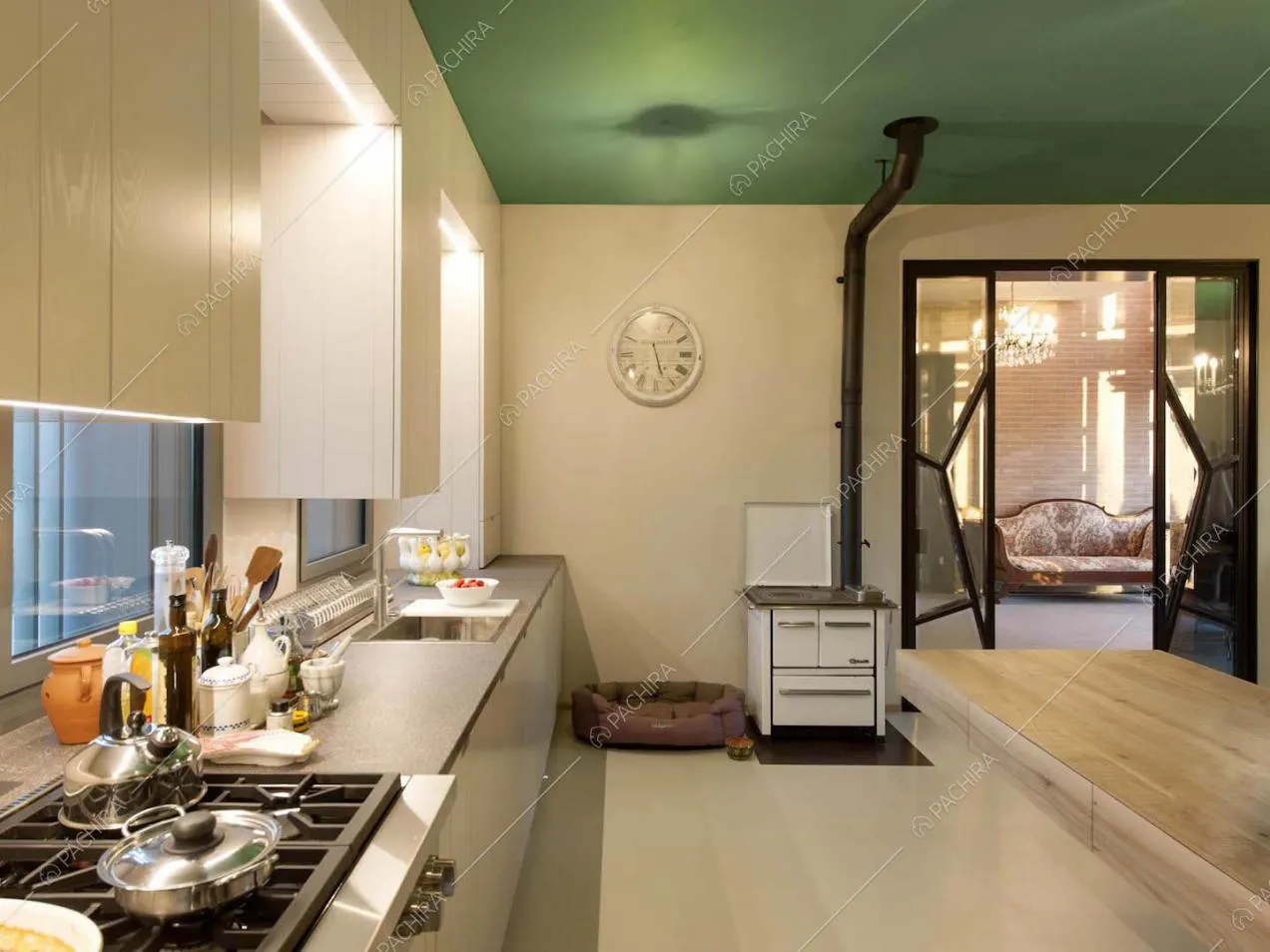 Grande cucina con fornelli a gas, pavimento bianco, soffitto verde e vista sul salotto