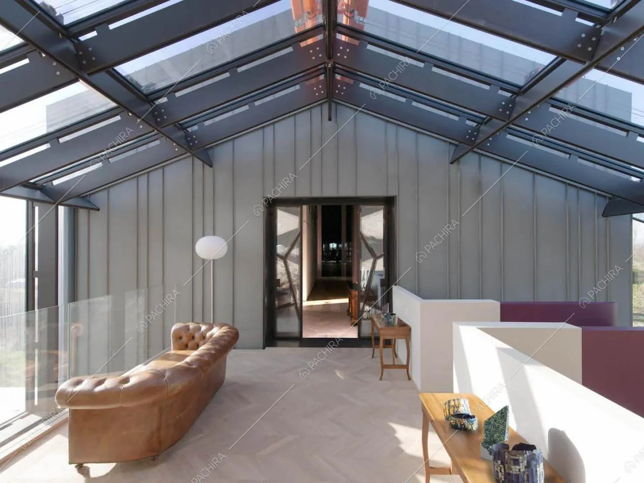 Solaio con pareti e soffitto in vetro con infissi neri e pavimento in parquet a spina di pesce