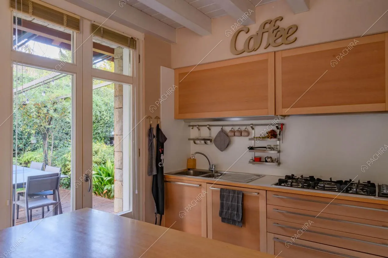 Cucina a parete in legno con fornelli a gas, tavolo da pranzo e porta-finestra