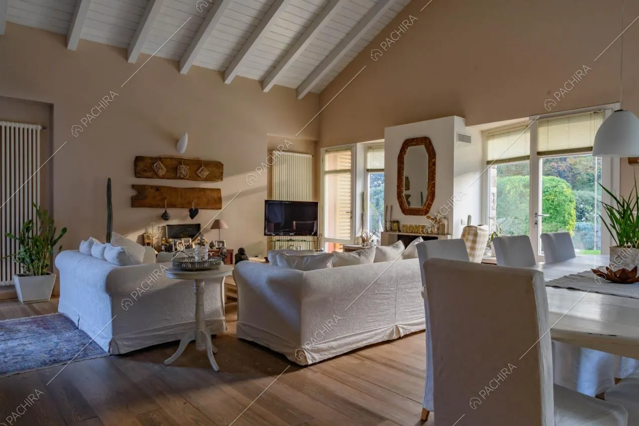 Tavolo da pranzo con sedie bianche nella zona living con travi bianche in legno a vista sul soffitto