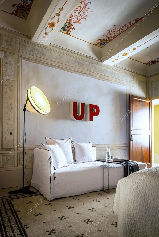 Dal letto matrimoniale nella camera con soffitto affrescato vista sul pouf bianco