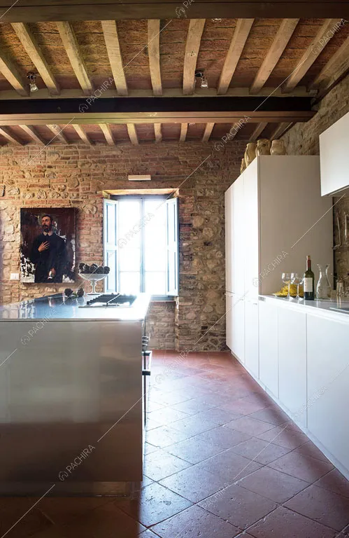 Cucina a isola in acciaio con fornelli a gas e soffitto in travi in legno a vista