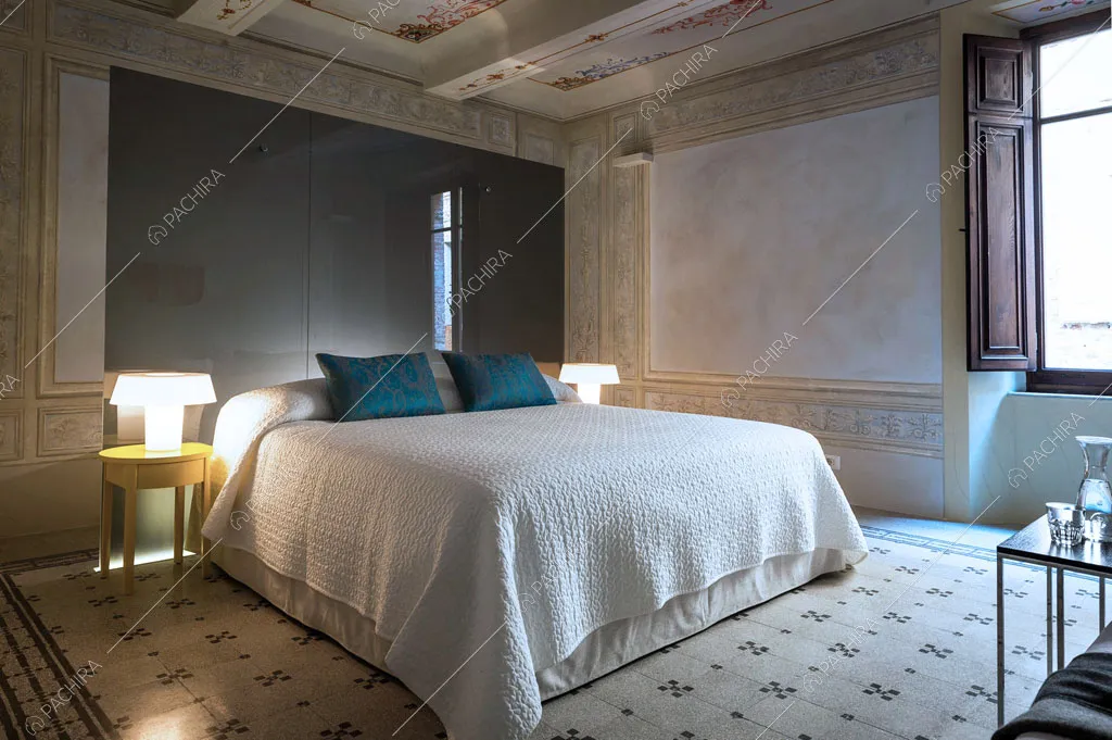 Letto matrimoniale nella camera da letto con parete in vetro e pavimento a fantasia geometrica