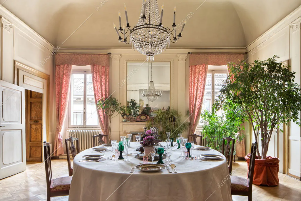 Tavolo da pranzo rotondo nella sala con boiserie alle pareti e pavimento in parquet