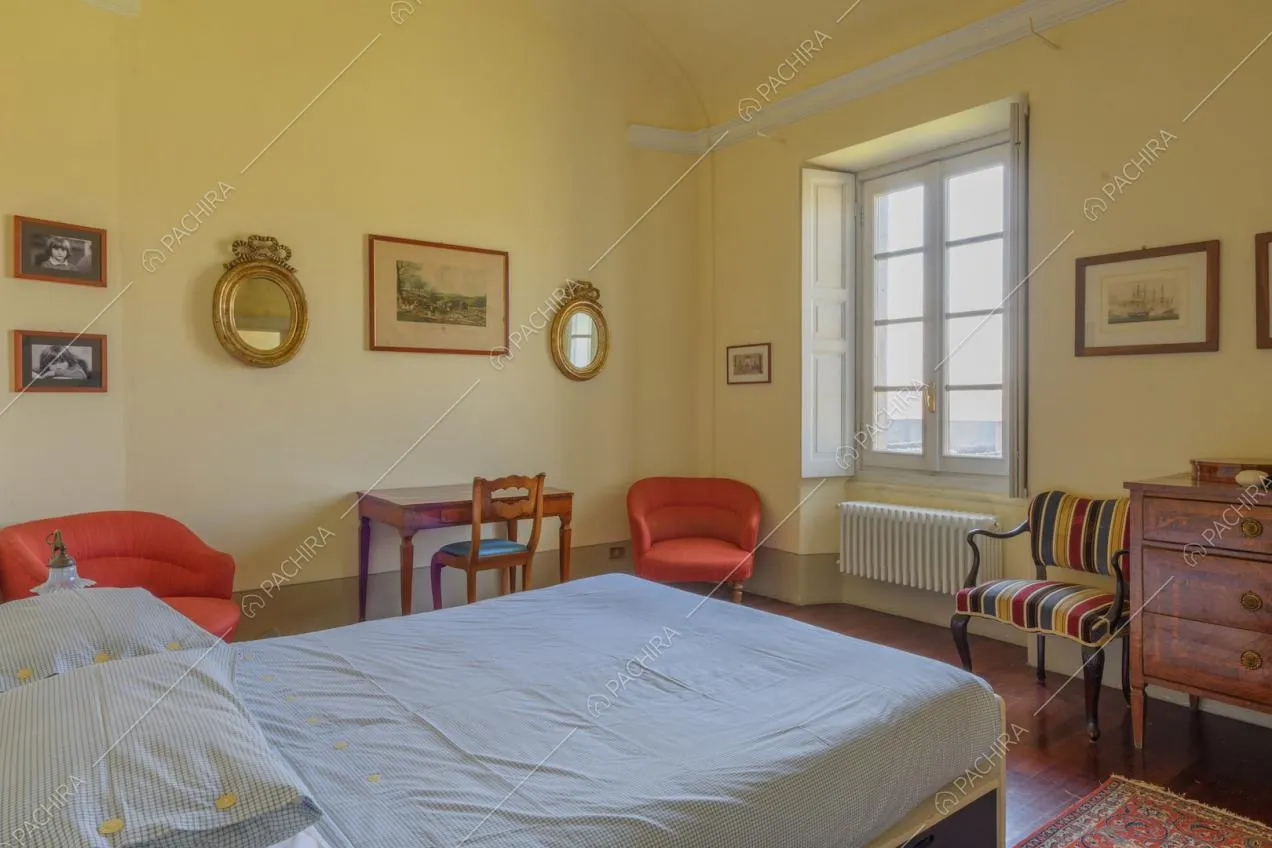 Letto matrimoniale nella luminosa camera con pareti gialle e pavimento in parquet
