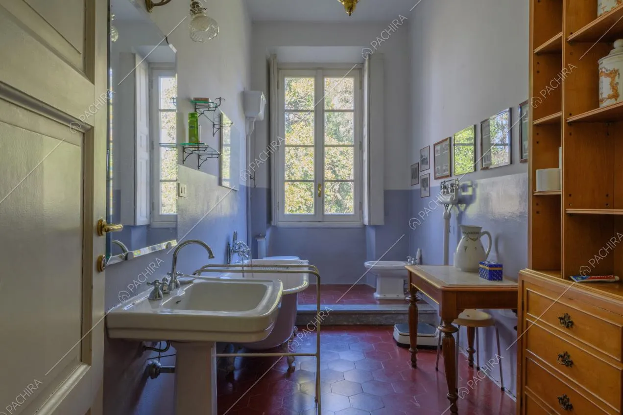 Ampio bagno con vasca, pareti bianche e azzurre e pavimento in piastrelle rosse