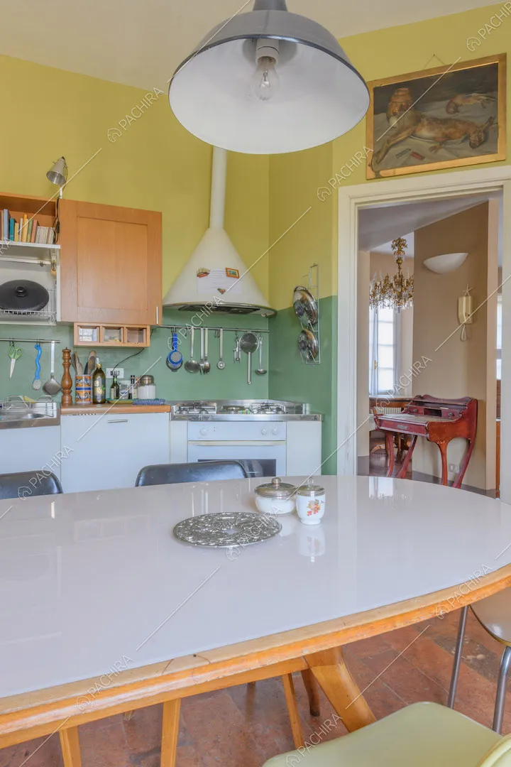 Tavolo da pranzo ovale nella cucina con fornelli a gas e pareti gialle e verdi