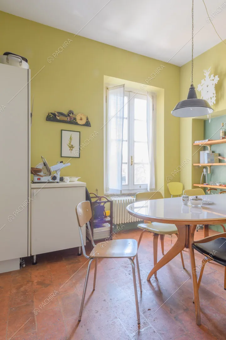 Pareti gialle della luminosa cucina con pavimento in cotto e tavolo da pranzo