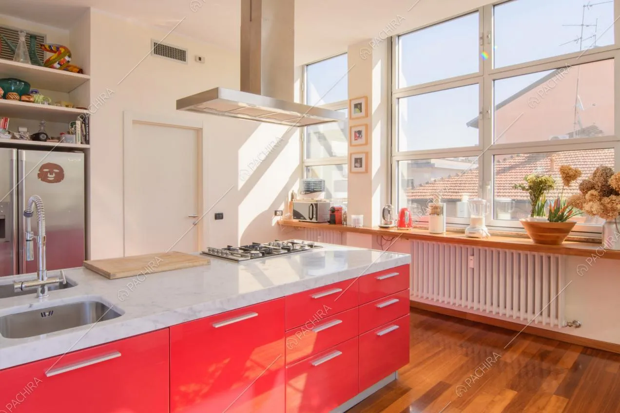 Isola rossa con piano da lavoro in marmo, fornelli a gas e pavimento in parquet
