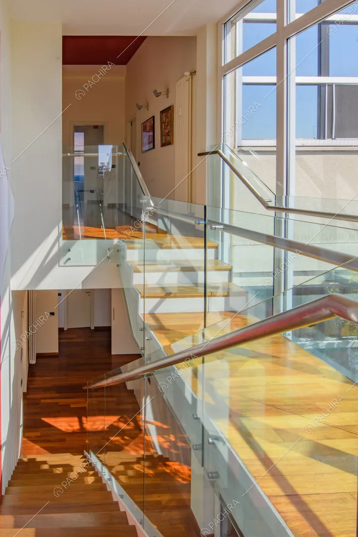 Scale e corridoio in parquet, parapetto in vetro e grandi finestre