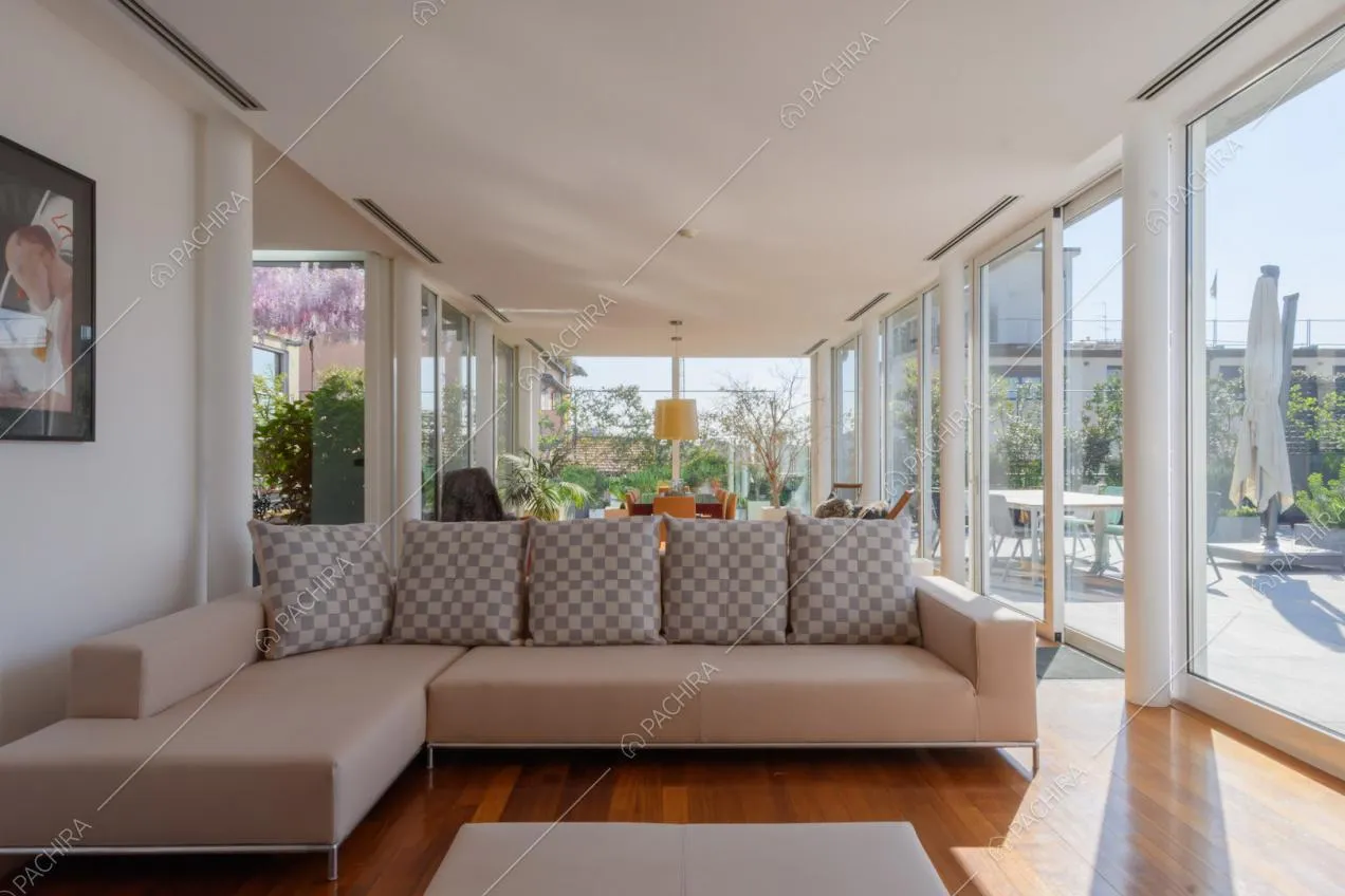 Divano angolare beige nella grande zona living con pareti in vetro e pavimento in parquet